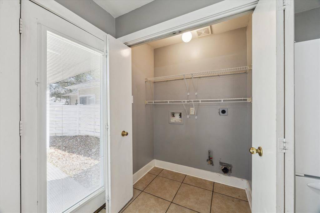 The utility room is conveniently tucked behind bi-fold doors in the kitchen, featuring built-in shelving for household storage.