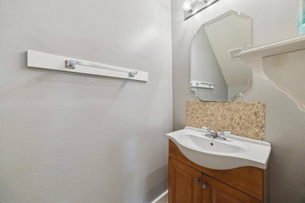 A first-floor powder bath is convenient for guests with a single sink vanity, mirror and vanity lights above.