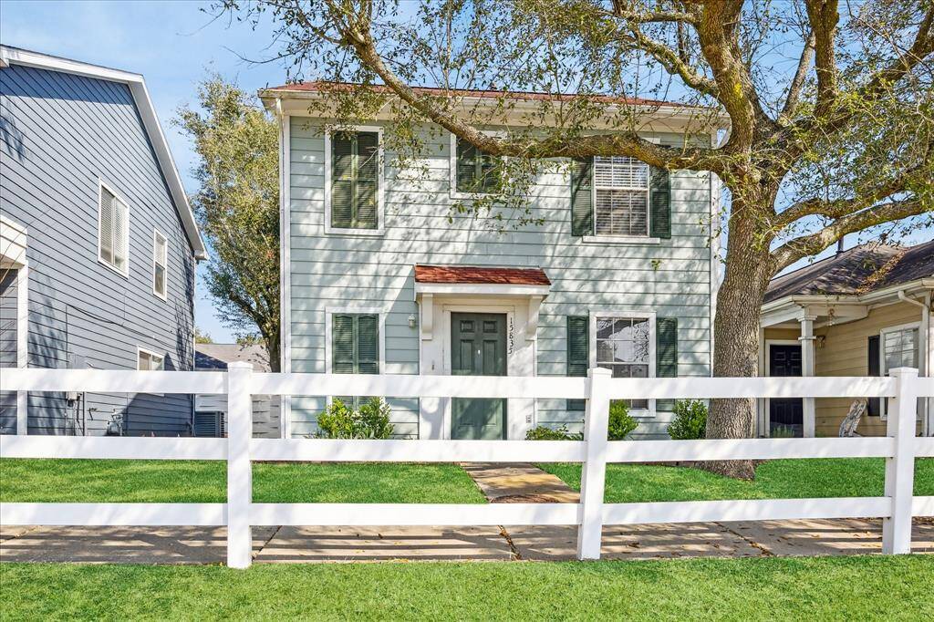 This charming home boasts classic curb appeal with a white picket fence, lush greenery, and a welcoming front porch, creating a picture-perfect first impression.