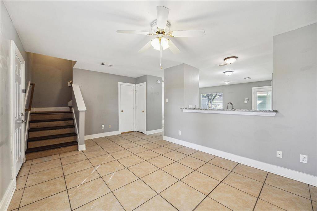 This open family room is a great space to welcome family and friends into your home. With tile flooring, neutral paint, a lit fan, and a handy pass-through bar to the kitchen.