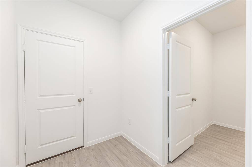 View of the hallway, located adjacent to the kitchen. To the right is the laundry room. To the right is the door that leads to the garage.