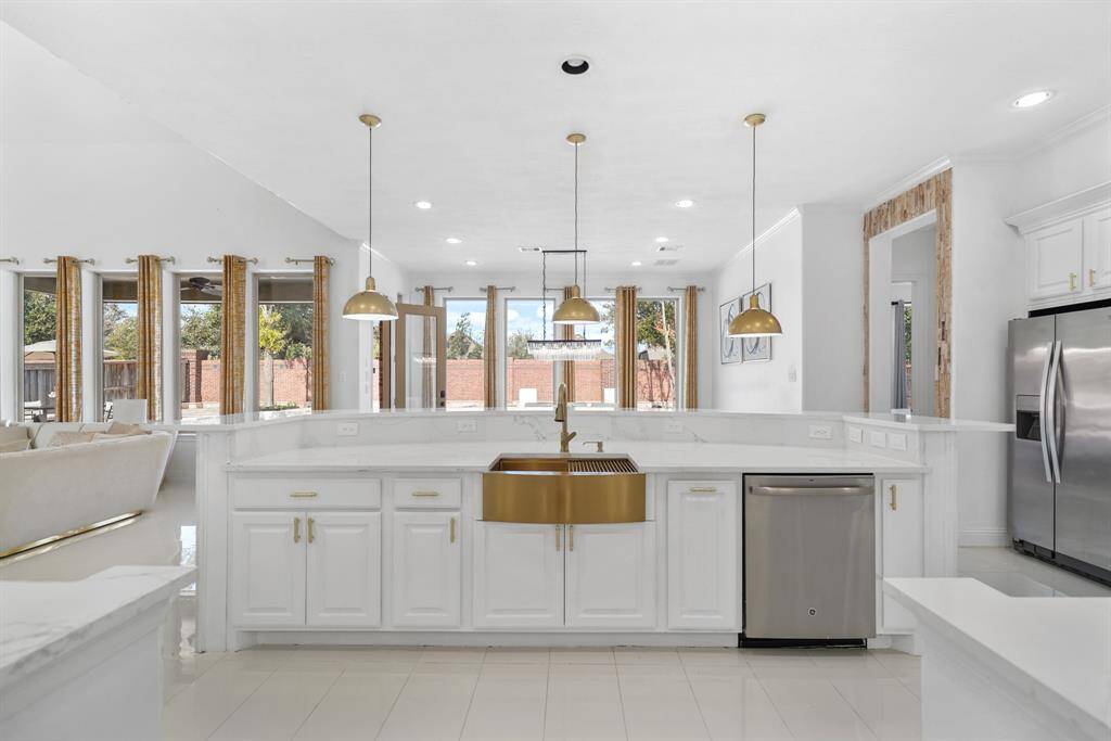 The kitchen showcases a spacious quartz waterfall island with sleek, polished edges, centered by a luxurious gold farmhouse sink and tap that adds a touch of opulence to the modern design.