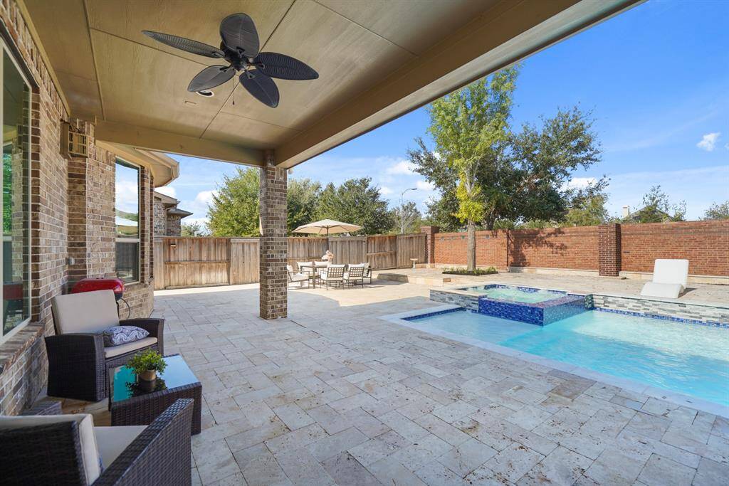 The oversized Backyard patio is fully covered, providing ample space for relaxation and entertainment, with elegant travertine flooring and unobstructed privacy, as the are no rear neighbors to disturb the tranquil atmosphere.