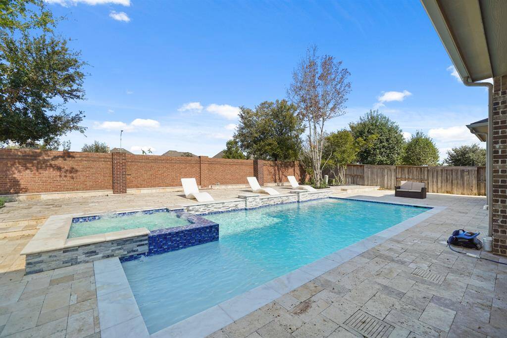 The resort style pool is expansive and luxurious, featuring an extra large design alongside a relaxing hot tub spa, creating a private oasis for leisure and rejuvenation.