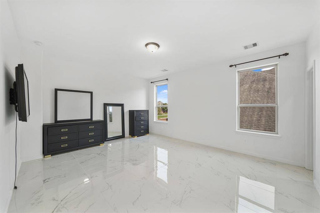 The secondary room showcases gleaming polished tile floors, with no bed, allowing the generous size of the space to stand out, perfect for versatile design possibilities.