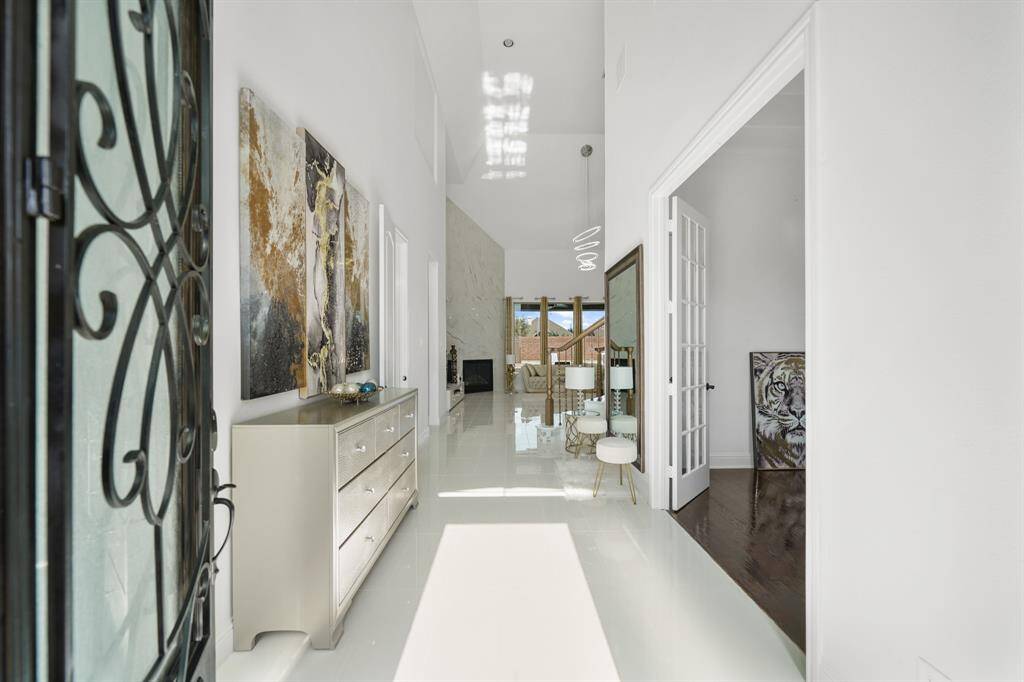 The entrance hallway welcomes you with soaring ceilings, a dazzling chandelier that casts a warm glow, and polished tiles creating an ambiance of elegance and spacious luxury.