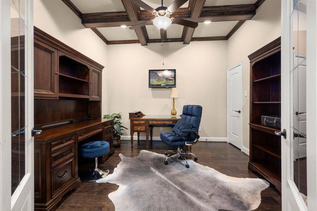 The home office just beyond the french doors, sits under wood coffered ceiling, with a ceiling fan adds a rich and elegant feel.