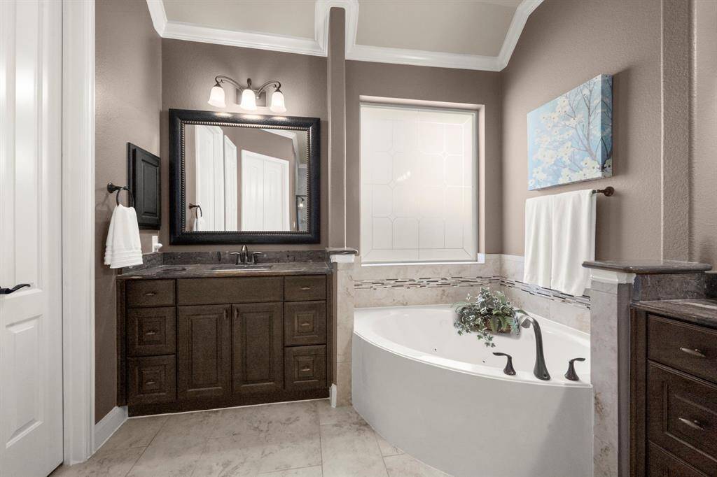 The spa-inspired ensuite is designed for relaxation, featuring a soaking tub, a walk-in shower, and dual vanities with premium granite countertops.