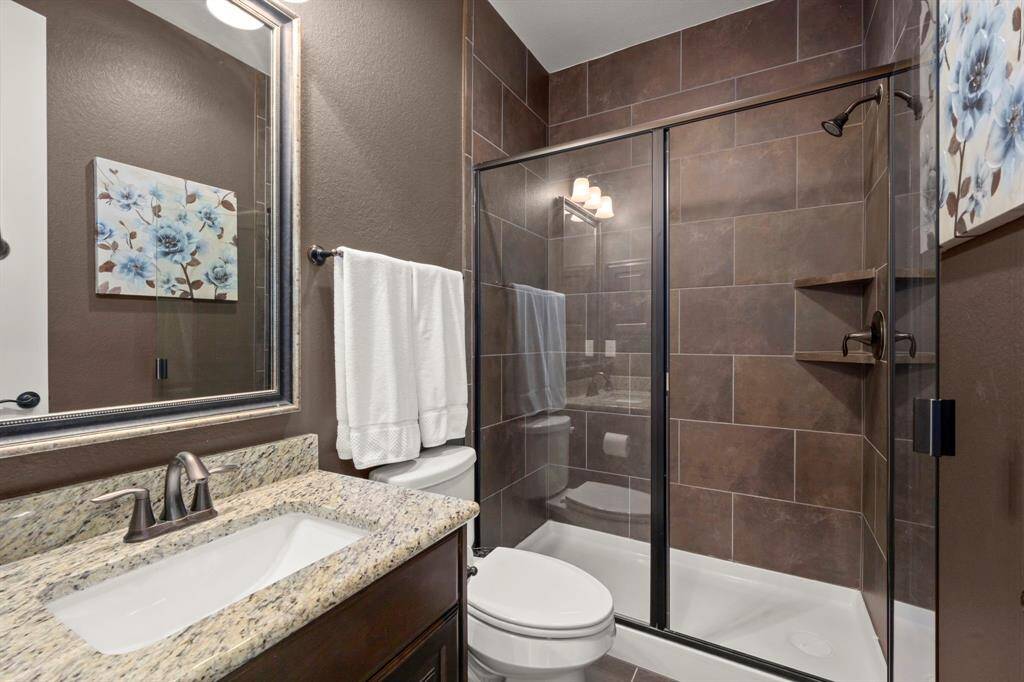 Granite countertops, premium cabinetry, and modern fixtures elevate this upstairs bathroom.