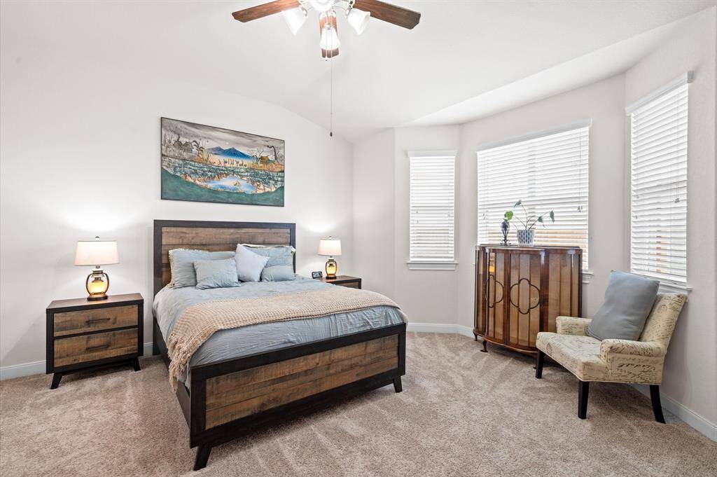 A heavenly primary suite features plush carpet and a sitting area in front of bay windows.