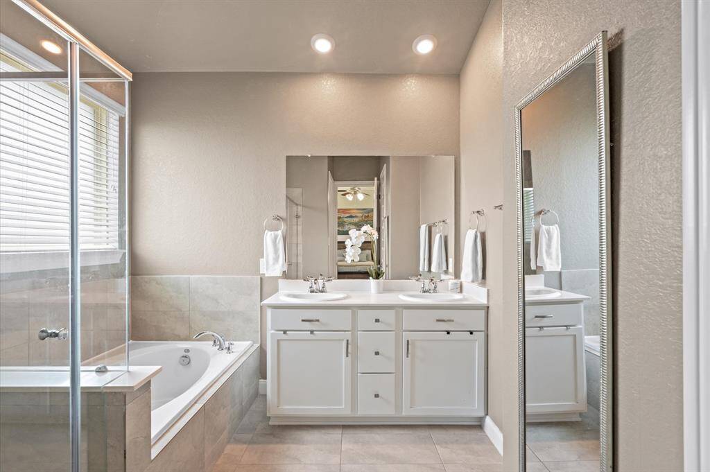 The primary bath offers a garden tub with tile surround, a separate shower, and a dual sink vanity.