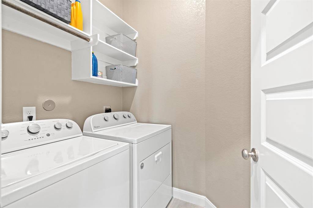 An indoor utility space includes shelving and a drying bar above the washer. The washer and dryer convey with the home.