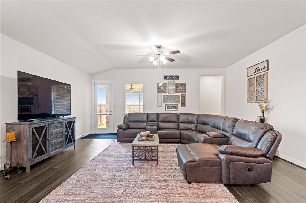 A generously sized living room or family room offers space for a sizable collection of furniture. The opening to the right leads to the primary suite and 2 secondary rooms. On the left you'll see access to the covered patio and backyard.