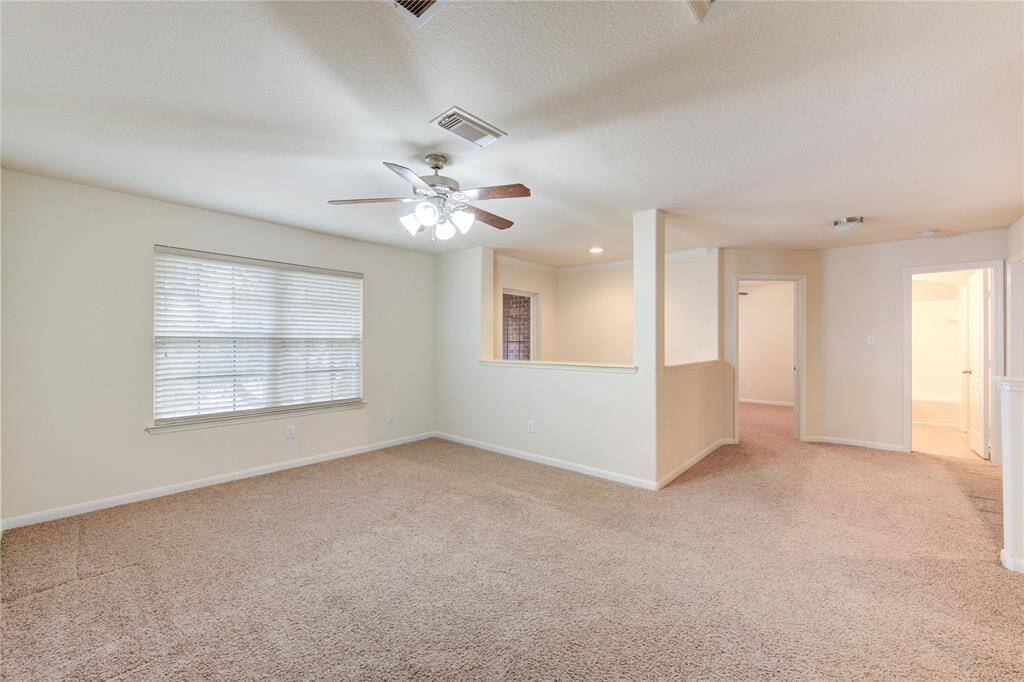 The second-floor living area offers plenty of space to create a magical game room or media center. Carpeted flooring and ceiling fan complete this room flawlessly.