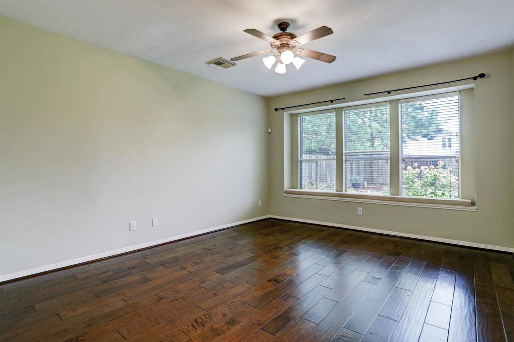 The primary bedroom is on the first floor with engineered wood flooring, a ceiling fan and windows overlooking the back yard.