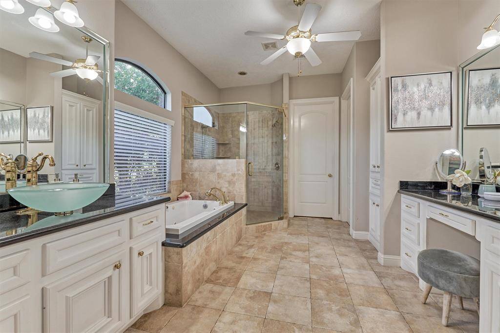 The primary bath has dual vanities, whirlpool tub, spacious shower, and water closet. Note the closet beyond has lots of natural light and generous storage.