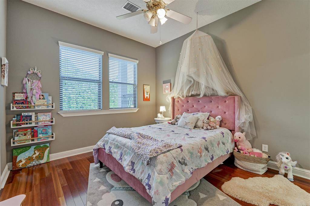 The first of two upstairs bedrooms has hardwood floors, a walk in closet, and an en suite bath.