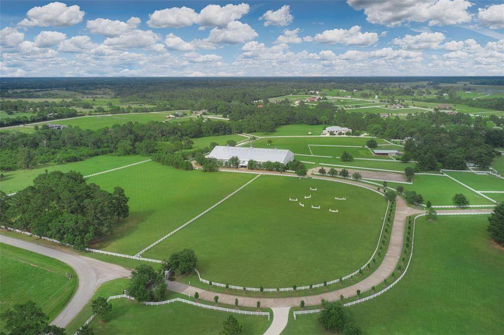 From this aerial view, we gain an appreciation for the large neighborhood lots. White fences separate properties. Here we see the outdoor riding arena which will provide schooling for the hunter/jumper rider. The indoor arena is just beyond.