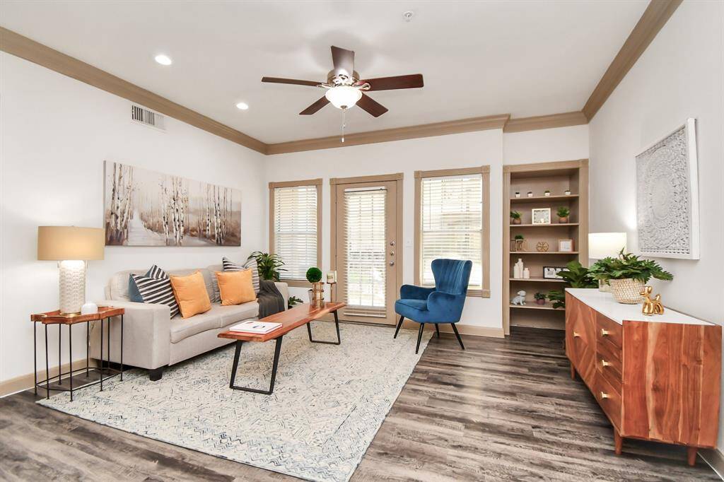 Well-lit living room, neutral color, French door leading to an outdoor space. Model unit.