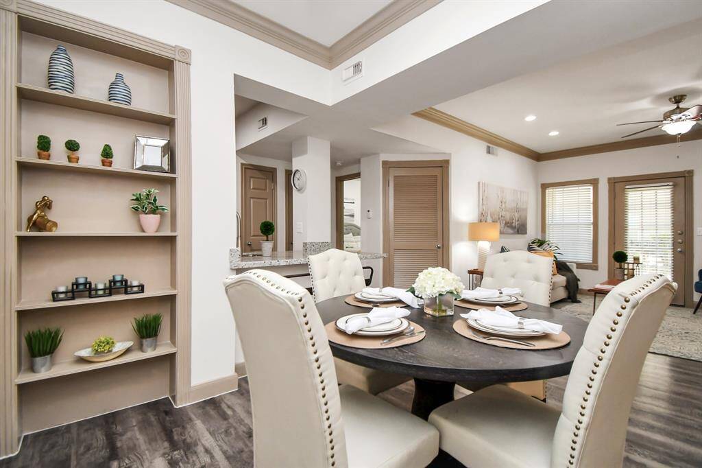Open-plan living space featuring a dining area, Neutral tones, built-in shelving. model unit.