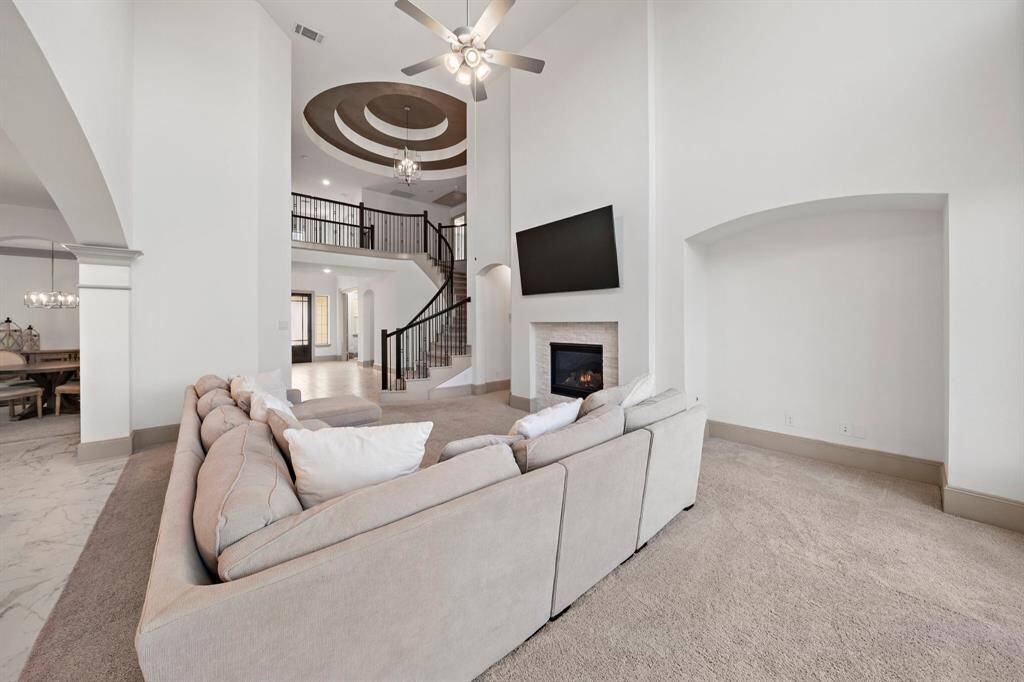 A stylish stone fireplace serves as the focal point of this living area, complemented by generous seating accommodations and abundant natural light.