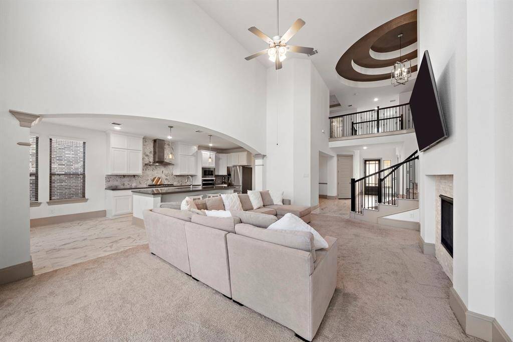 Notice the architectural details of this sizable living area, from the elegant curved staircase to the custom ceiling accents, adding sophistication to the entertainment space.