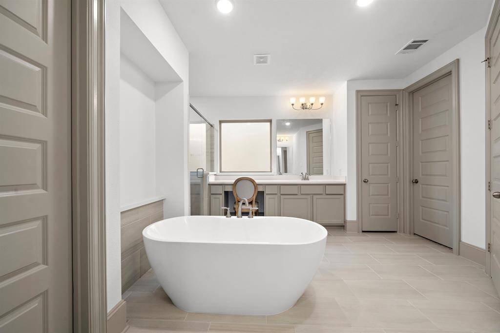A spacious walk-in shower with custom tilework and a frameless glass enclosure adds both elegance and functionality to the primary bath.