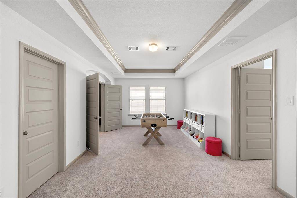 The second-floor hallway impresses with its open layout and elegant architectural details, including a striking circular ceiling feature and sleek wrought iron railing. Its design seamlessly connects the upstairs spaces while adding a touch of modern sophistication.