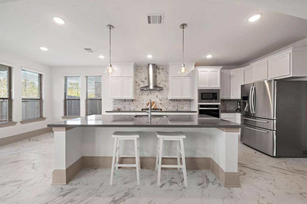 Prepare meals with ease in this modern kitchen fitted with new stainless steel appliances, sleek granite countertops, a custom backsplash, and multiple built-in cabinets. It also boasts a breakfast area and a vast island with counter seating—providing the perfect spot for casual dining or entertaining.
