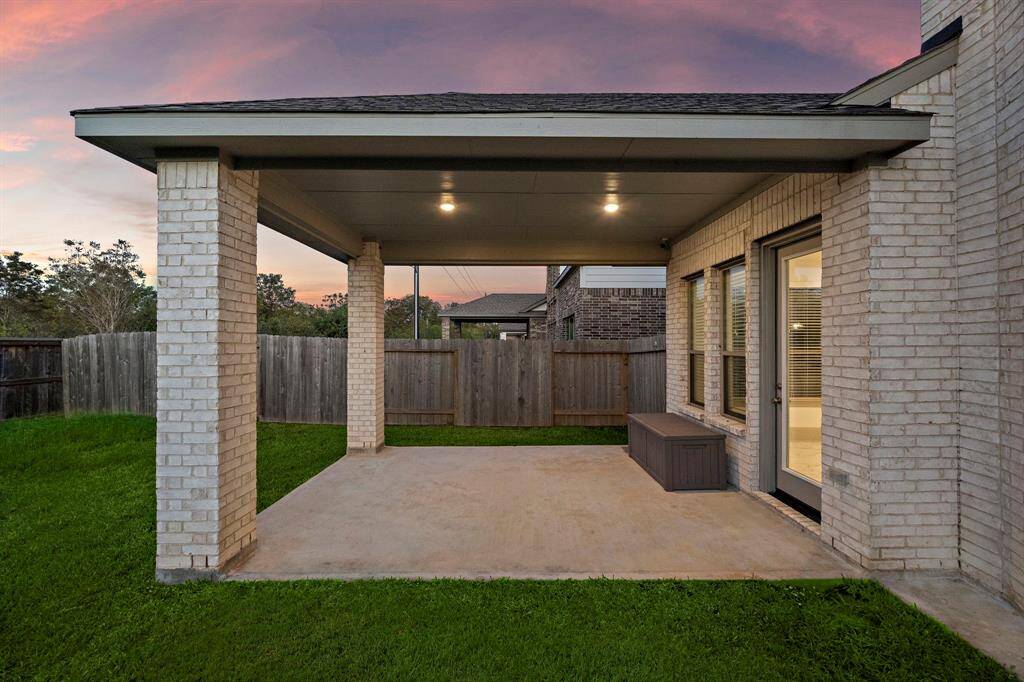 The covered patio invites year-round enjoyment with its generous space, ideal for hosting gatherings or unwinding while overlooking the lush green backyard.