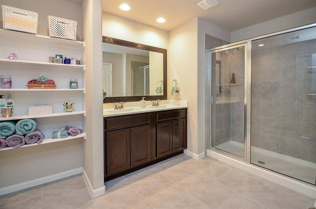 A functional and spacious master bathroom featuring a walk-in shower, a large vanity, and plenty of storage space.