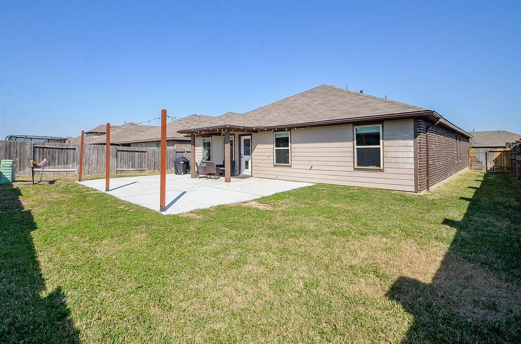 Expansive backyard featuring an extended concrete patio, providing more space to enjoy the outdoors with less lawn maintenance. The patio is enhanced with beautiful lighting, creating a cozy and inviting atmosphere—perfect for gatherings and celebrations.