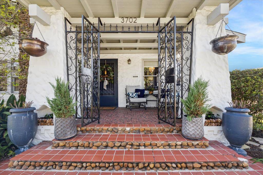 The grand porch entry is constructed of stone pillars with beamed ceilings and rod iron gates.