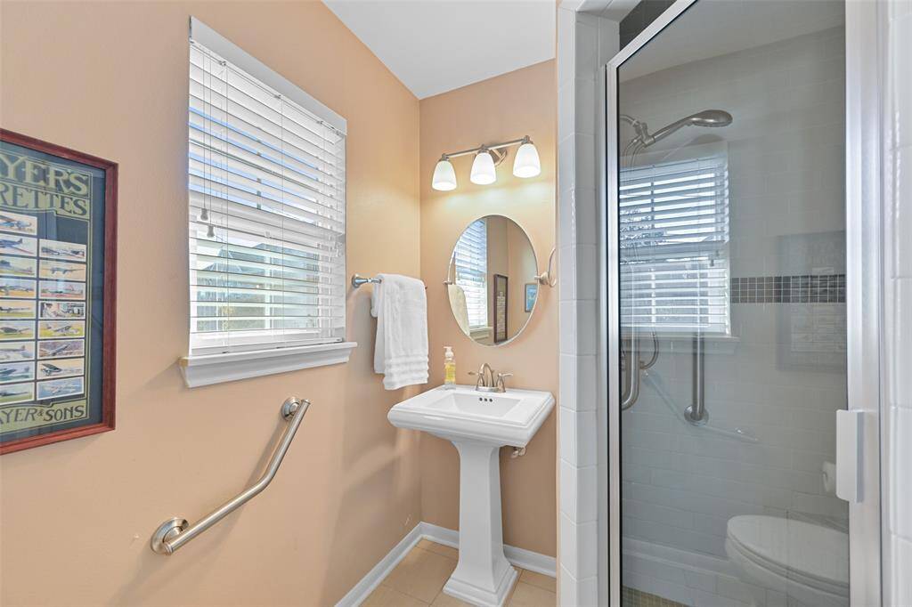 Pedestal sink, glass enclosed tiled shower and linen closet in the ensuite bath