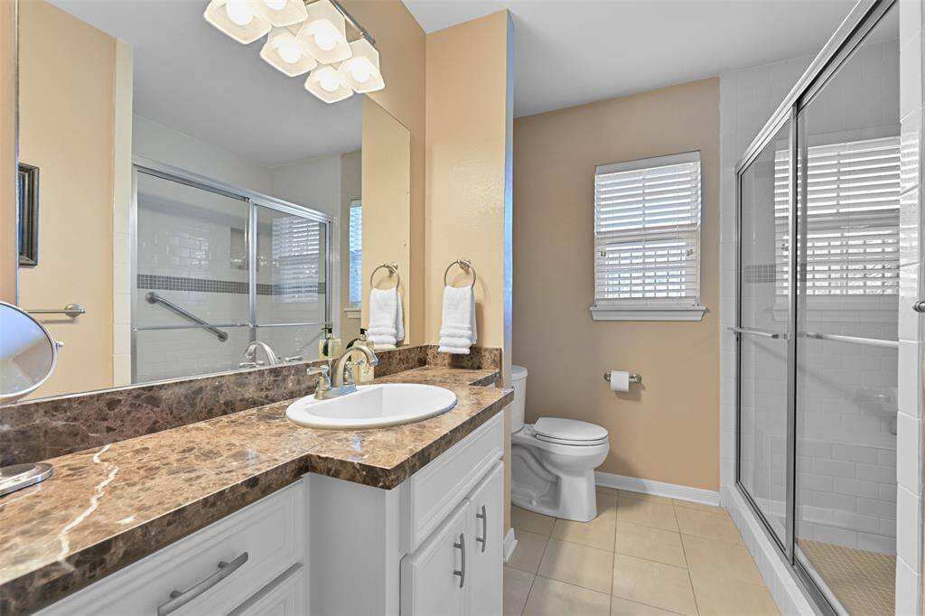 The hall bathroom has a large glass enclosed shower and linen closet . The granite vanity top has ample counter space