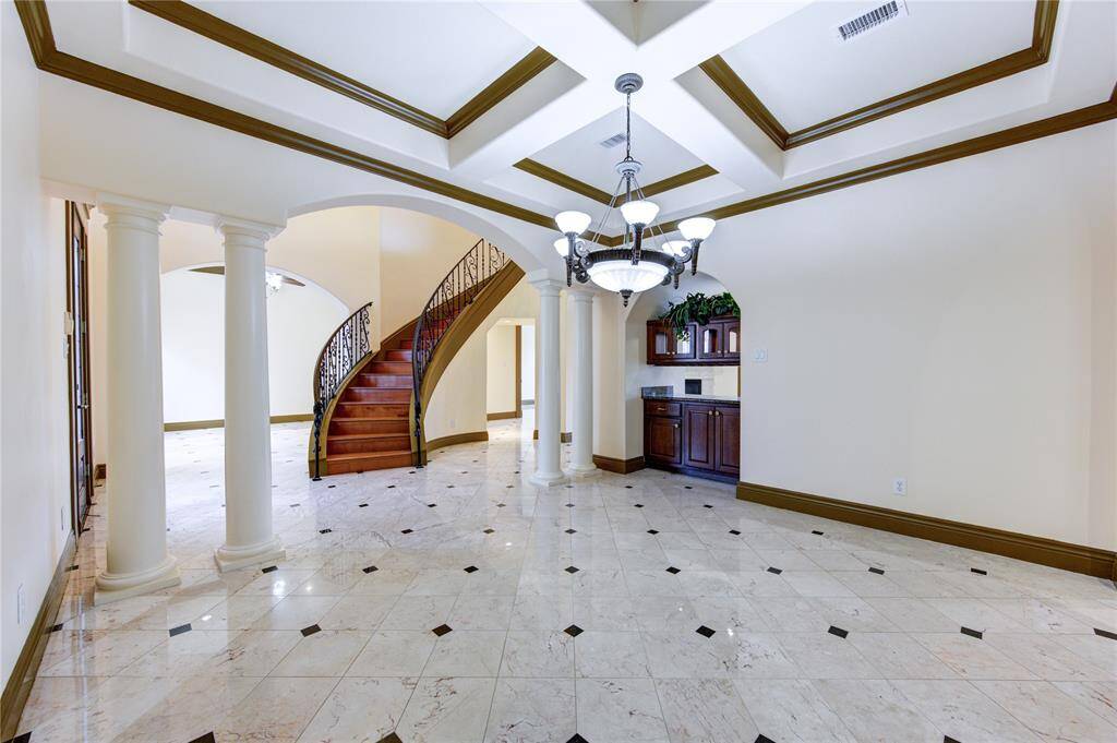 This is a bright, clean laundry room with ample storage, featuring white cabinetry and a single sink, set against beige walls and tiled flooring, with a window providing natural light.