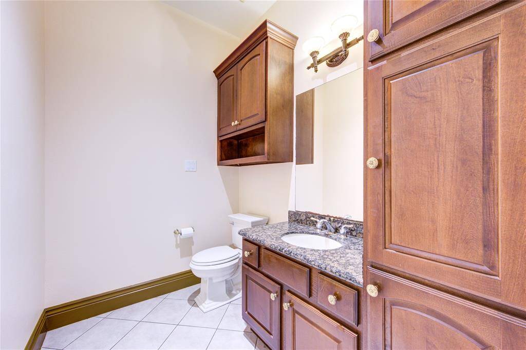 This is a spacious, corner walk-in pantry with multiple white shelves, providing ample storage for kitchen essentials, and it features a tiled floor for easy maintenance.