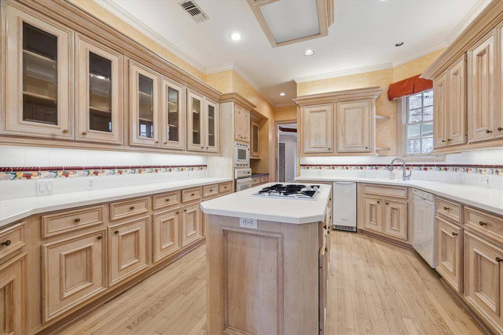 Large kitchen with Corian countertops, glass-front cabinets, gas cooktop, recessed lighting and miles of storage.
