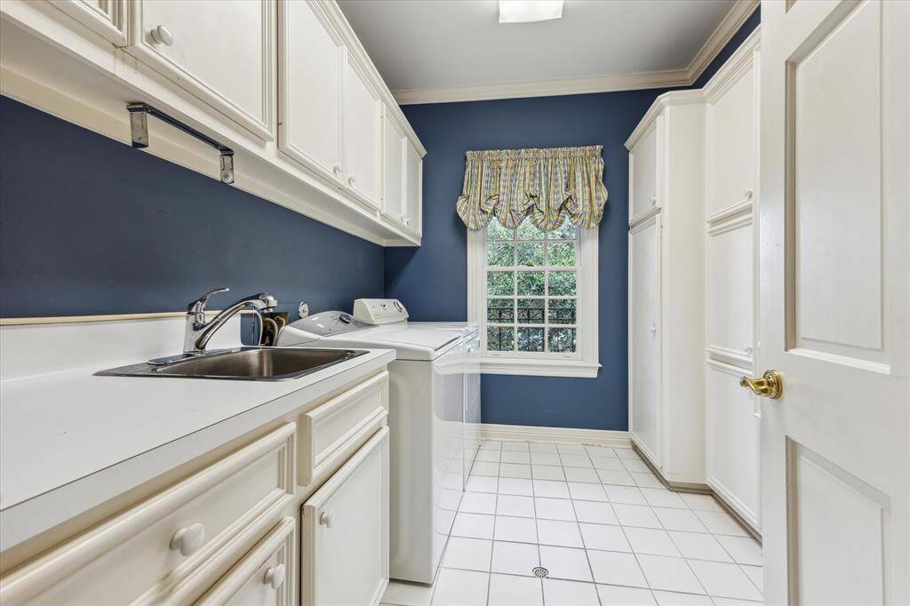 2nd story laundry room with wall of storage cabinetry, sink, folding counter.