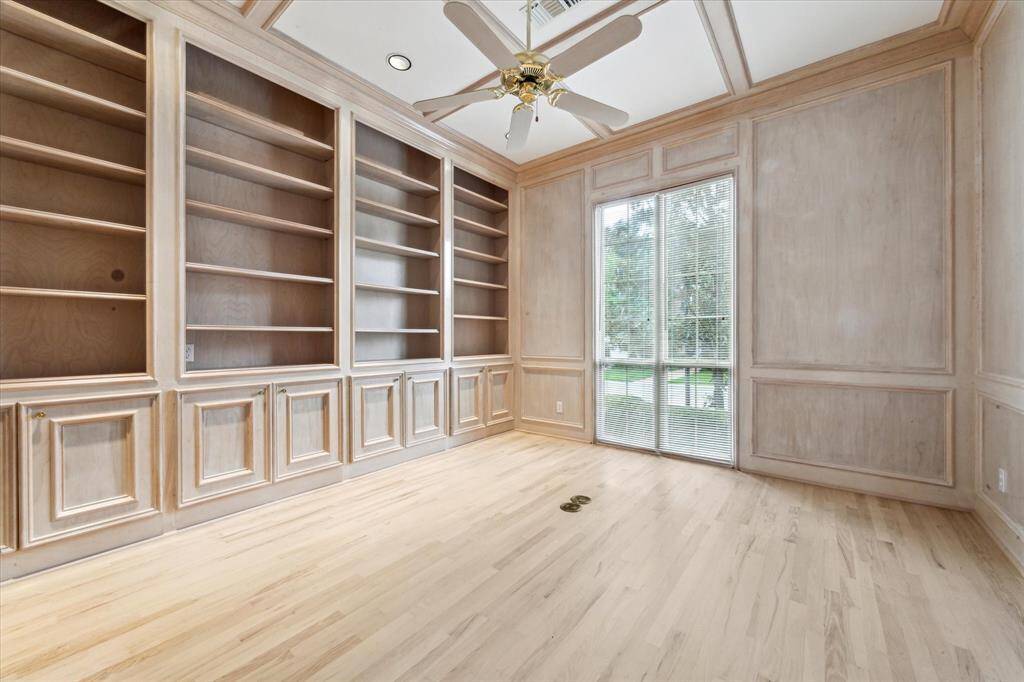 Library adjacent to entry with floor to ceiling cabinetry and shelving, coffered ceiling, ample storage cabinets and closet.