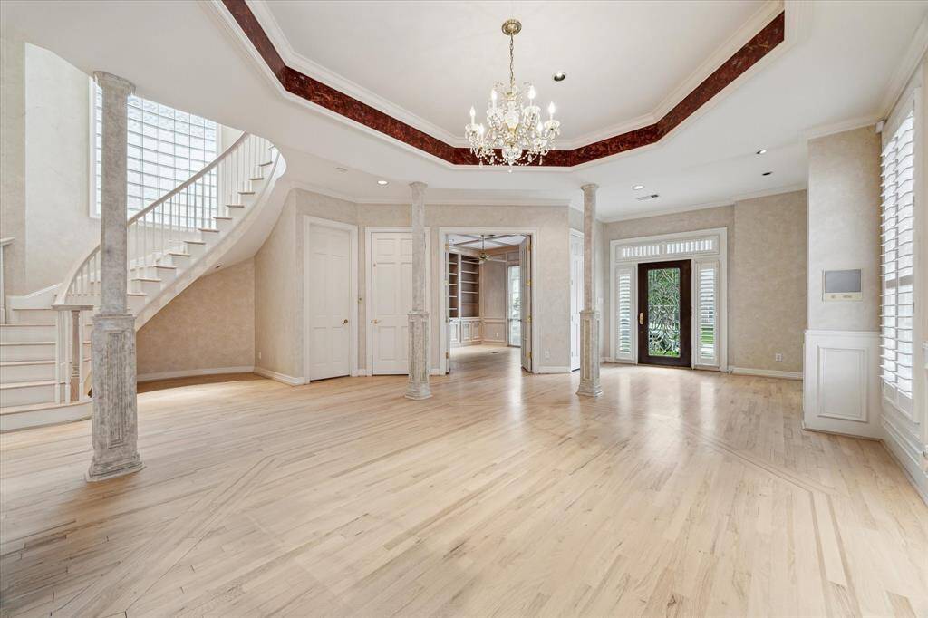 View from dining room looking back towards front entry and library. Elevator and powder bath are to the left of the library doors. Note inset ceiling in dining room, which is mirrored by the inset wood pattern on the floor.