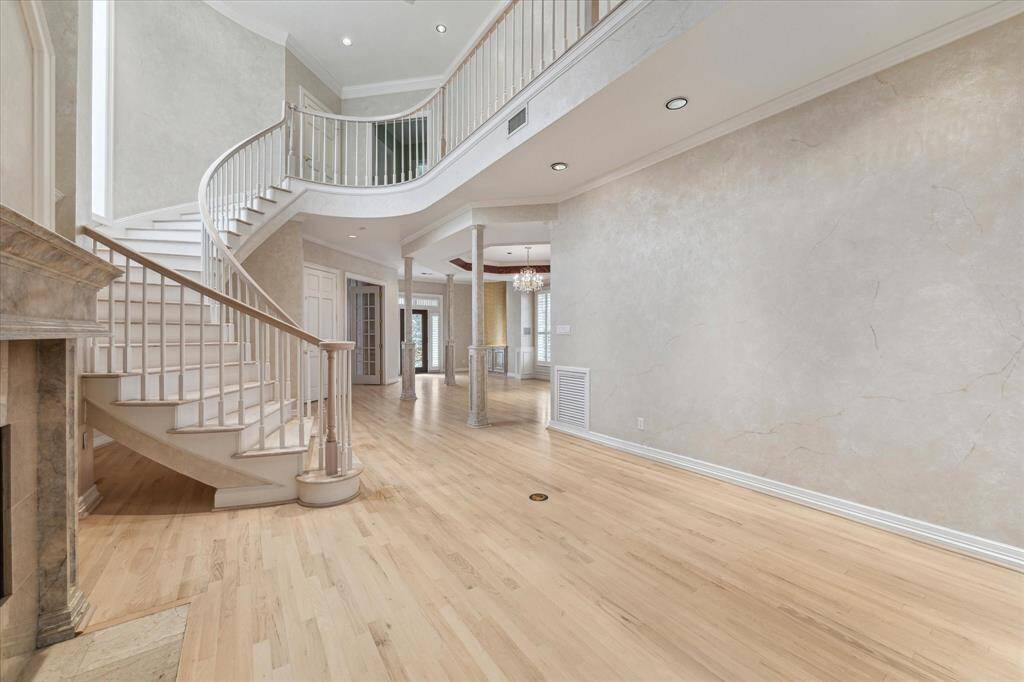 View from living room area of sweeping front staircase.  Doorway at the top of the stairs leads to the primary bedroom suite.