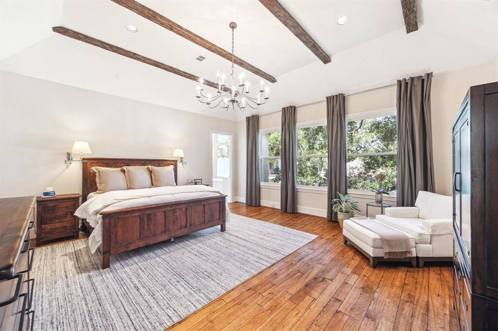 Massive primary suite features beamed ceilings, chandelier, recessed LED lighting, and fantastic treetop views through northern exposure.