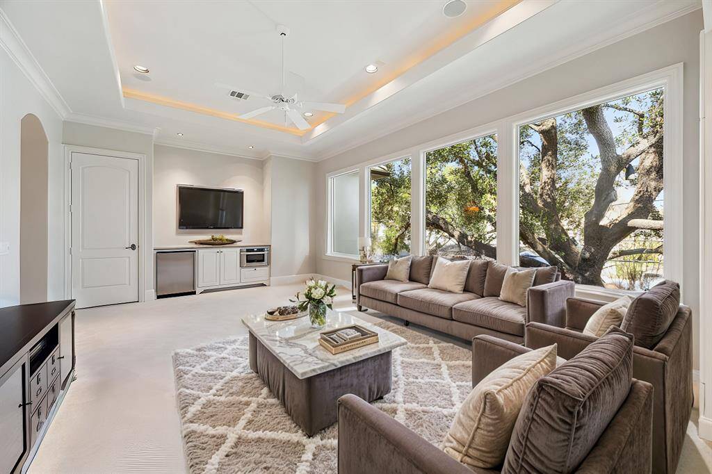 The essential versatile room. Large surround sound-capable media room/game room/upstairs den features cove lighting, built in refrigerator and microwave and wall of north-facing windows offering treetop view of a magnificent oak with dramatic landscape illumination. Virtually Staged.