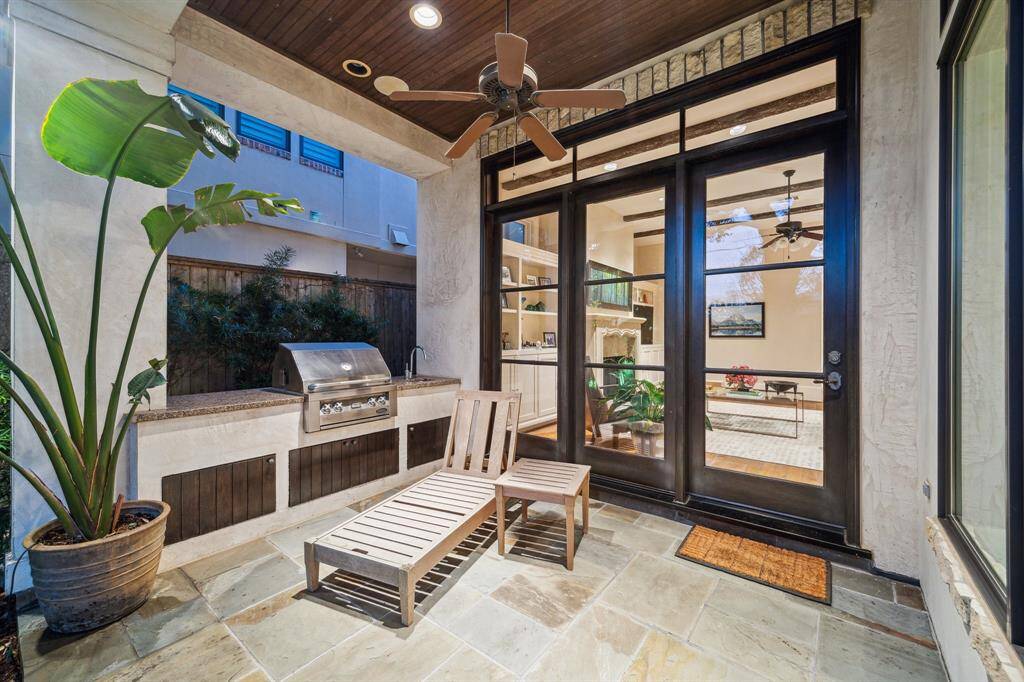 Slate floored covered patio with rotisserie, grill and sink. Glass wall leads to family room.