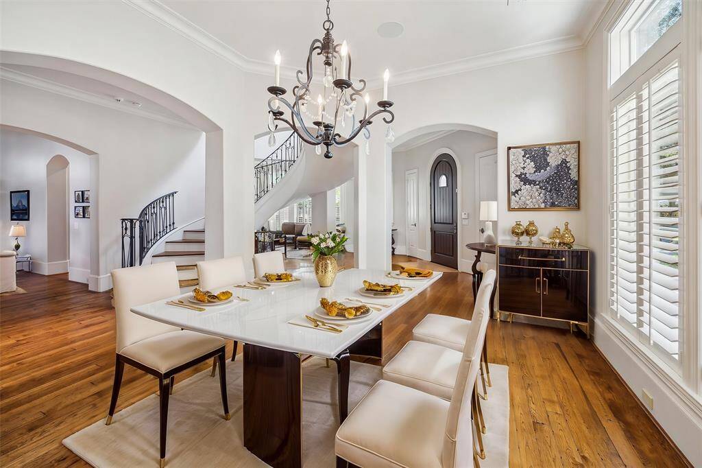 Elegant flow through spacious rooms bathed in natural light. Formal dining room with Western exposure, transomed wall of windows with plantation shutters, art, sconce and chandelier lighting. Virtually Staged.