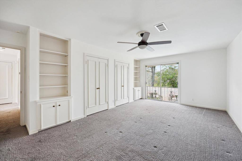 Spacious second bedroom featuring elegant built-in shelving, ideal for storage and display.