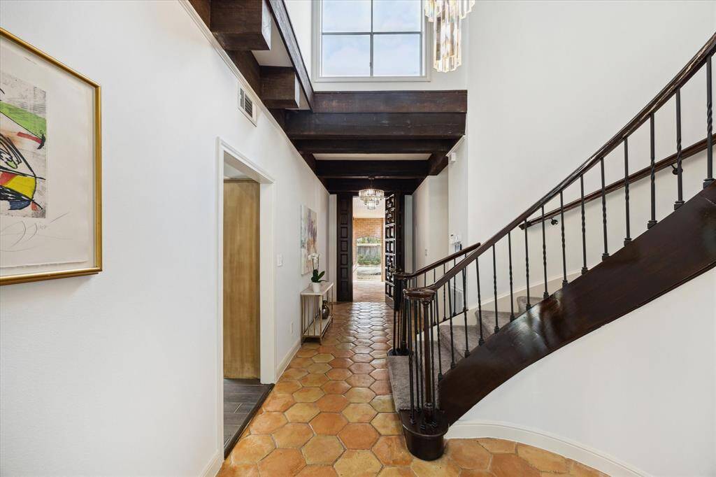 This enchanting home features a spiral staircase and a window above the door, flooding the space with natural light and Spanish-inspired charm.