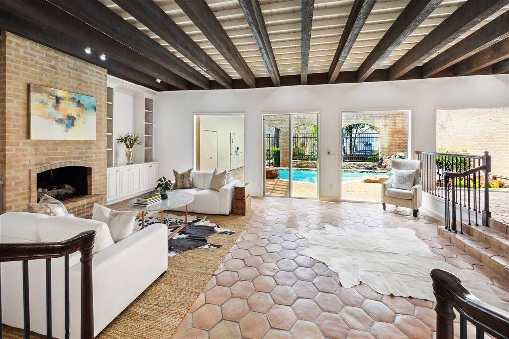 Step down into the spacious living area featuring stunning wood beam ceilings and captivating views of the pool and lush greenery.