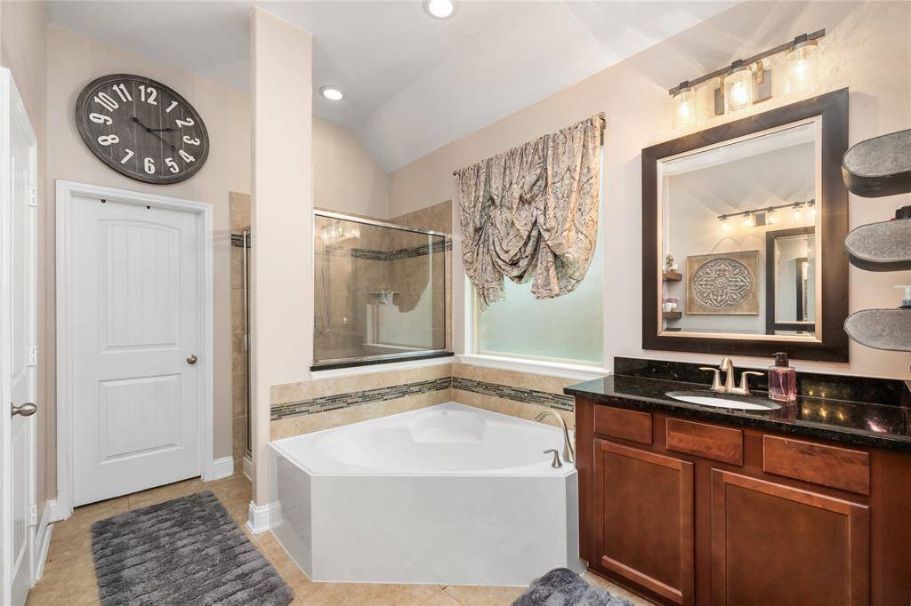 Soaking tub, walk-in shower, dual vanities with granite counters, and clean modern lighting- this Primary Bathroom has everything you need to unwind